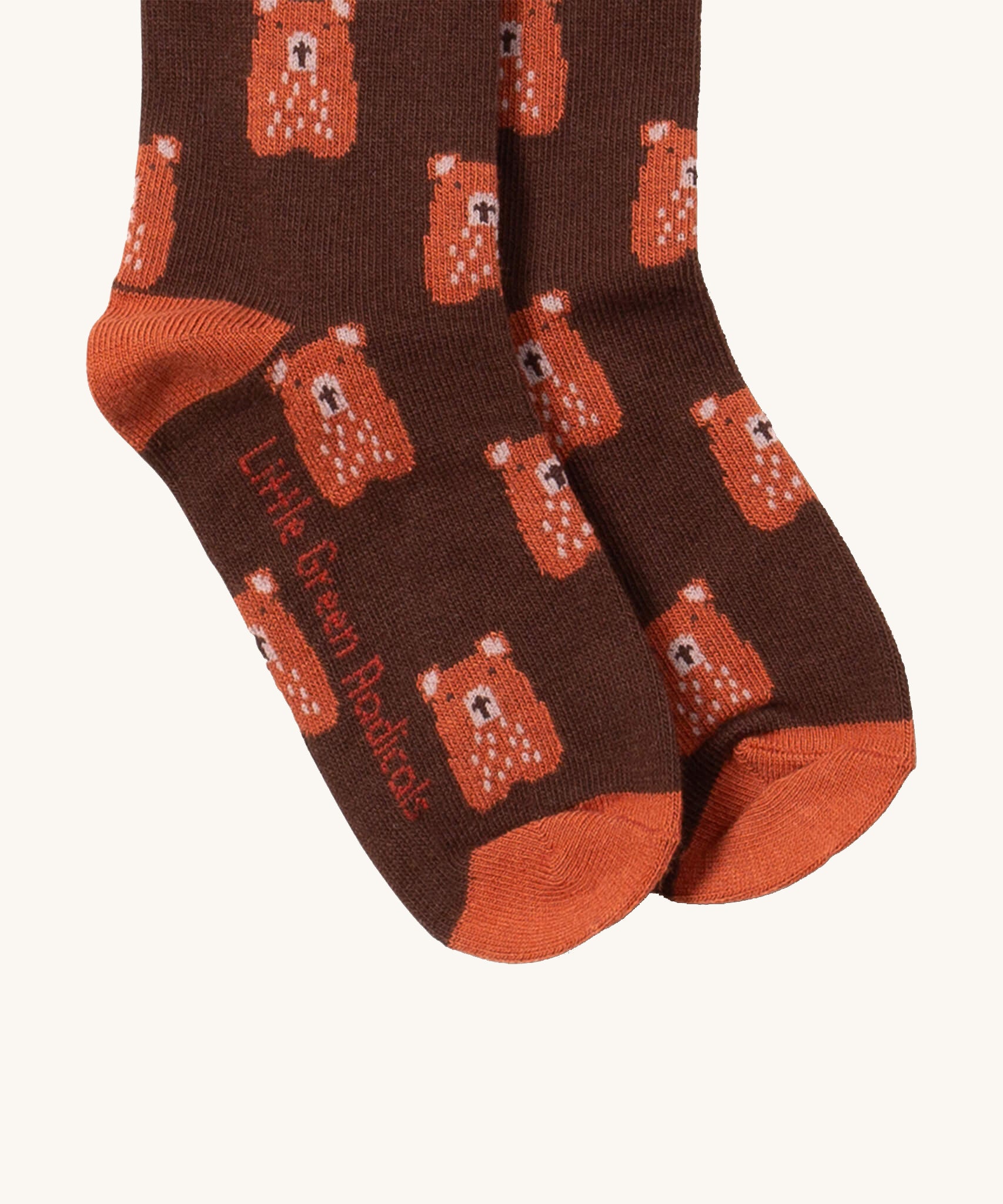 A close up of the teddy bear Little Green Radicals ankle socks showing teddy bear design with light brown trim and brand name on the sole on soft organic cotton fabric