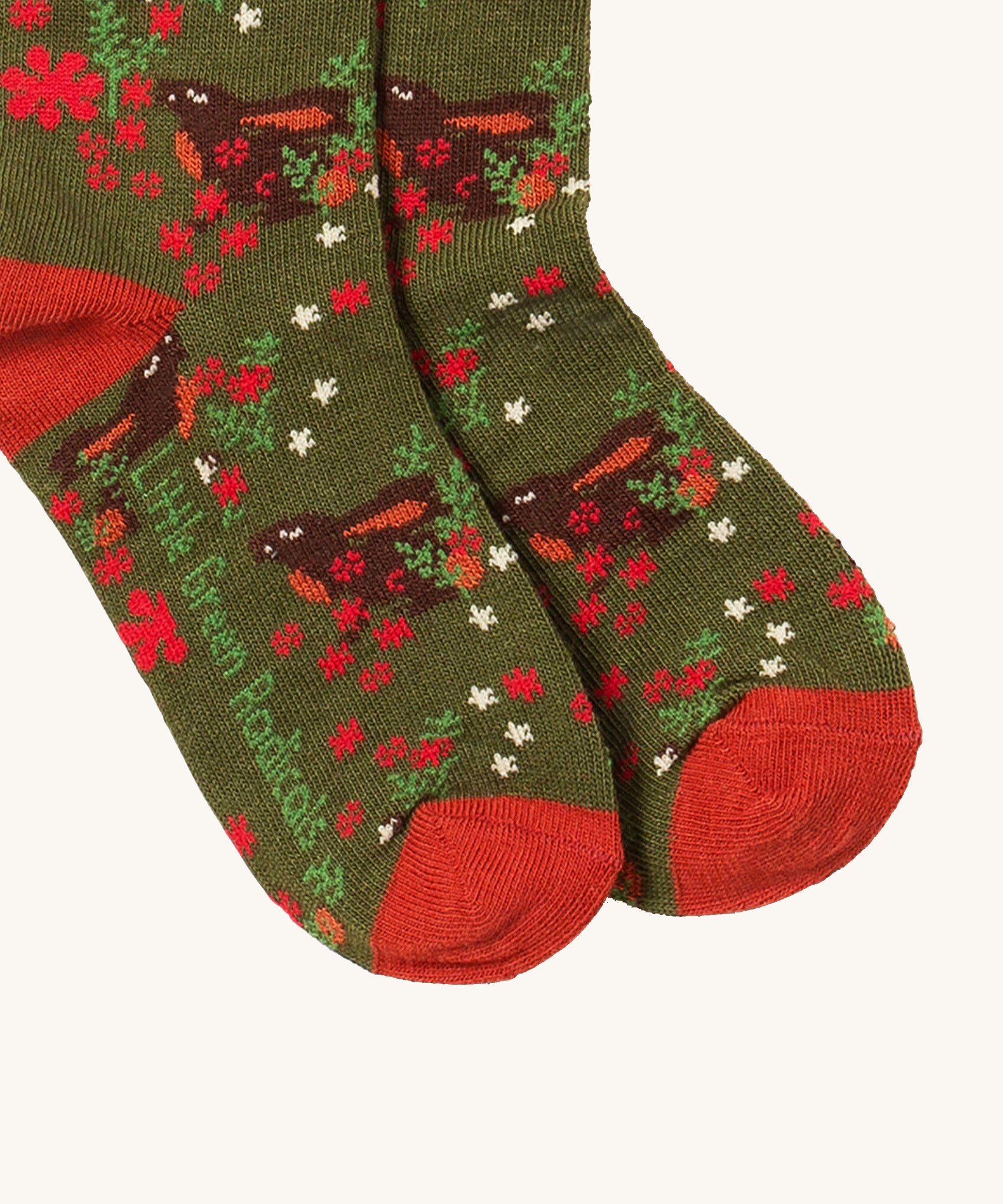 A close up of the Little Green Radicals winter rabbit ankle socks. Showing the rabbit design detail and red trim with the brand name on the the sole on dark green organic cotton fabric.
