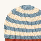 A close up of the Little Green Radicals knitted beanie in blue stripes. Showing the thick blue and cream knit detail on organic cotton fabric.