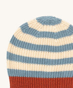 A close up of the Little Green Radicals knitted beanie in blue stripes. Showing the thick blue and cream knit detail on organic cotton fabric.