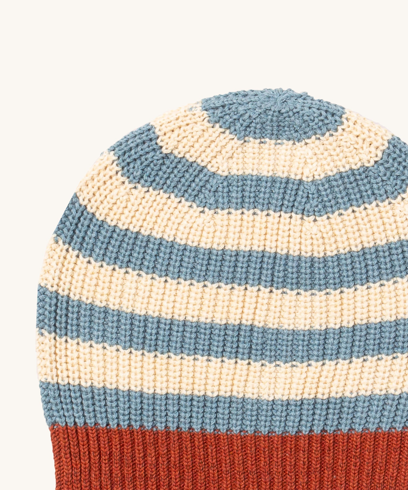 A close up of the Little Green Radicals knitted beanie in blue stripes. Showing the thick blue and cream knit detail on organic cotton fabric.