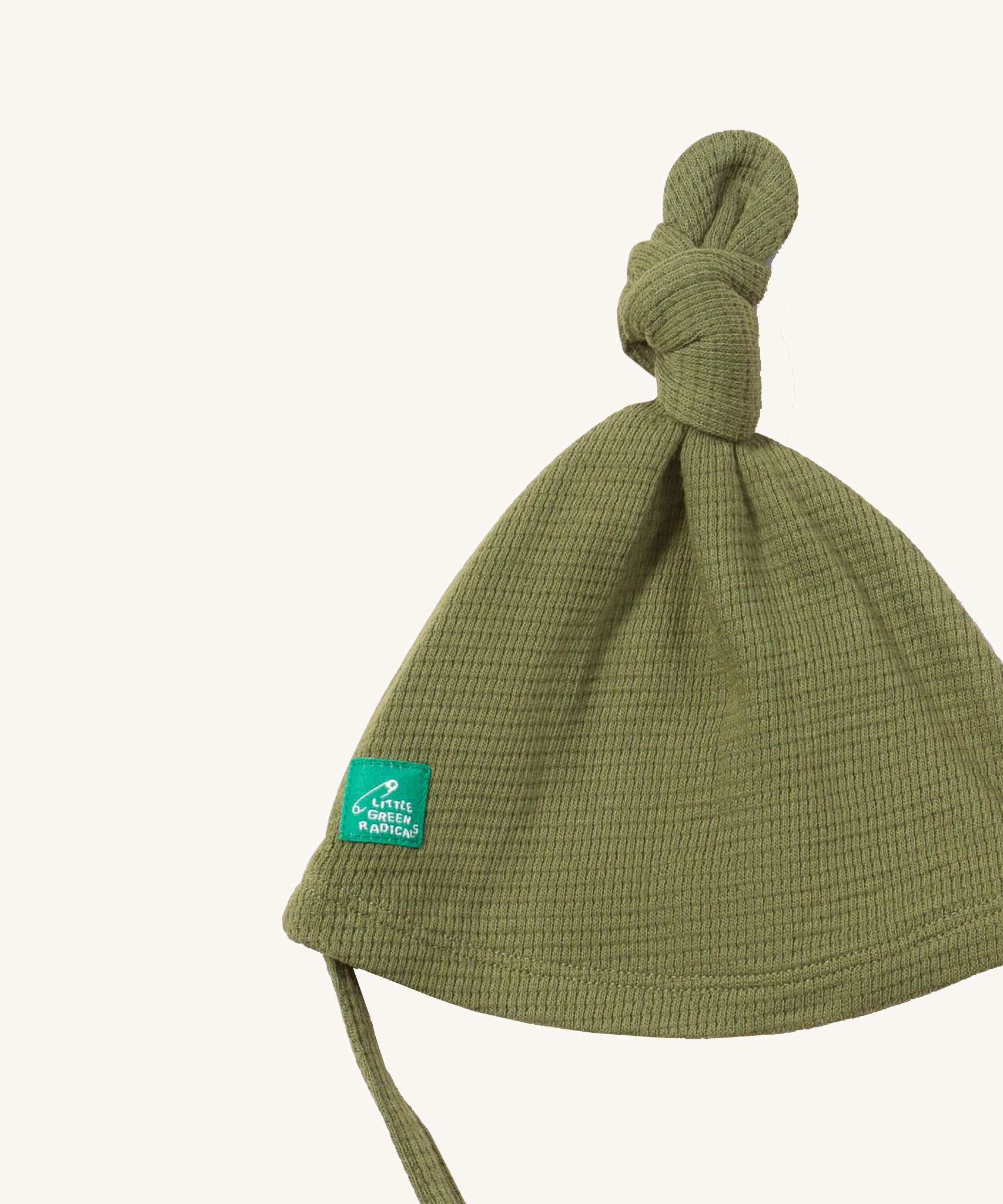 A close up of the Little Green Radicals chive waffle tie hat showing the knot detail  on green organic cotton fabric