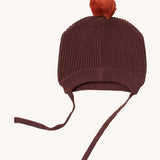Little Green Radicals chocolate knitted beanie. A brown knitted GOTS organic cotton beanie style hat Features matching brown ties for a secure fit and a light brown pom pom