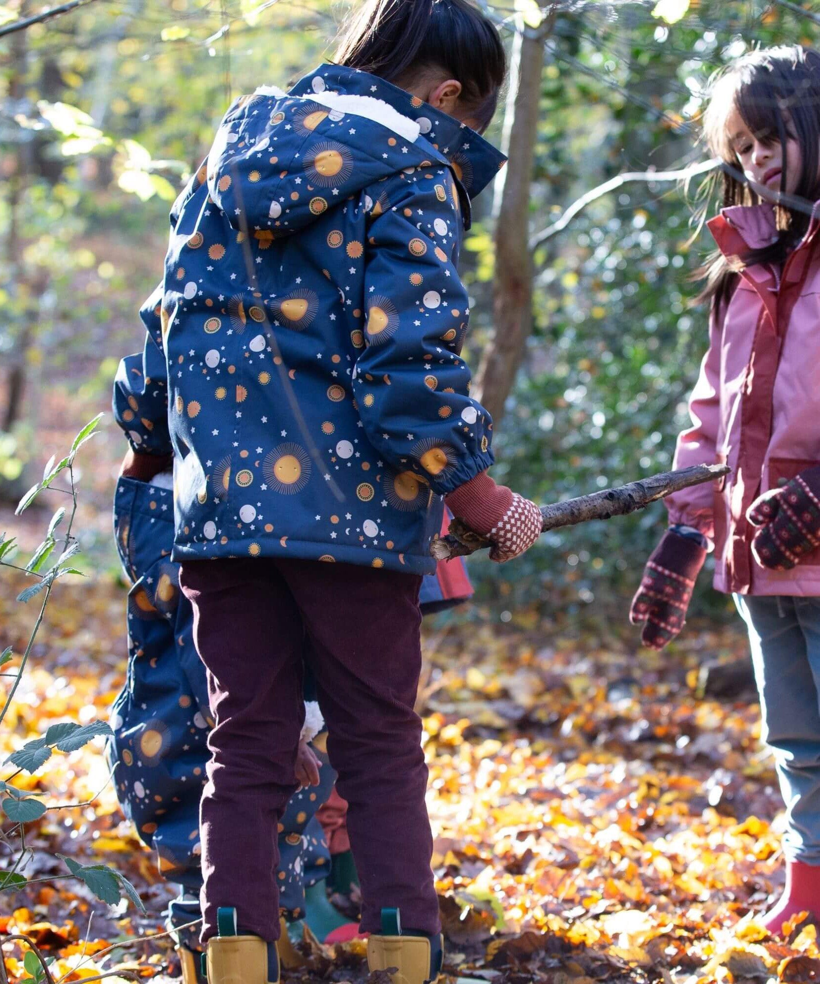 A child playing in the woods and wearing the chocolate comfy trousers. A corduroy style trouser made from GOTS organic cotton fabric.