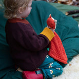 A child sitting down and wearing the Little Green Radicals turquoise rainbow joggers. A soft GOTS organic cotton jogger with cute prints of rainbows.