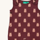 A close up of the Little Green Radicals everyday dungarees in brown bears showing the button fastener detail on the shoulder straps and brown bear print on dark maroon organic cotton fabric.