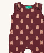 A close up of the Little Green Radicals everyday dungarees in brown bears showing the button fastener detail on the shoulder straps and brown bear print on dark maroon organic cotton fabric.