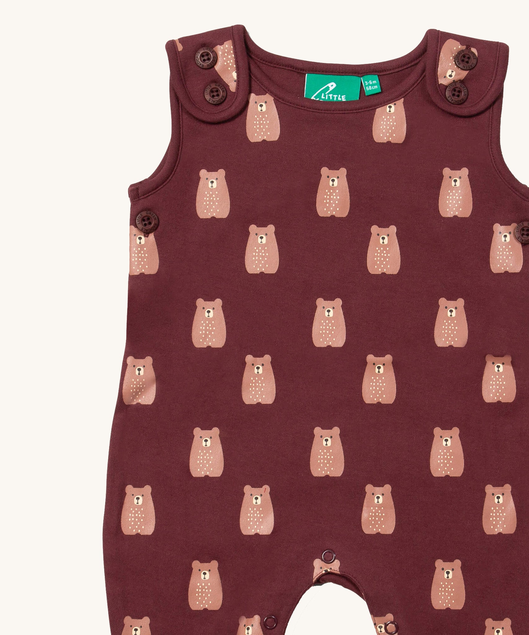 A close up of the Little Green Radicals everyday dungarees in brown bears showing the button fastener detail on the shoulder straps and brown bear print on dark maroon organic cotton fabric.