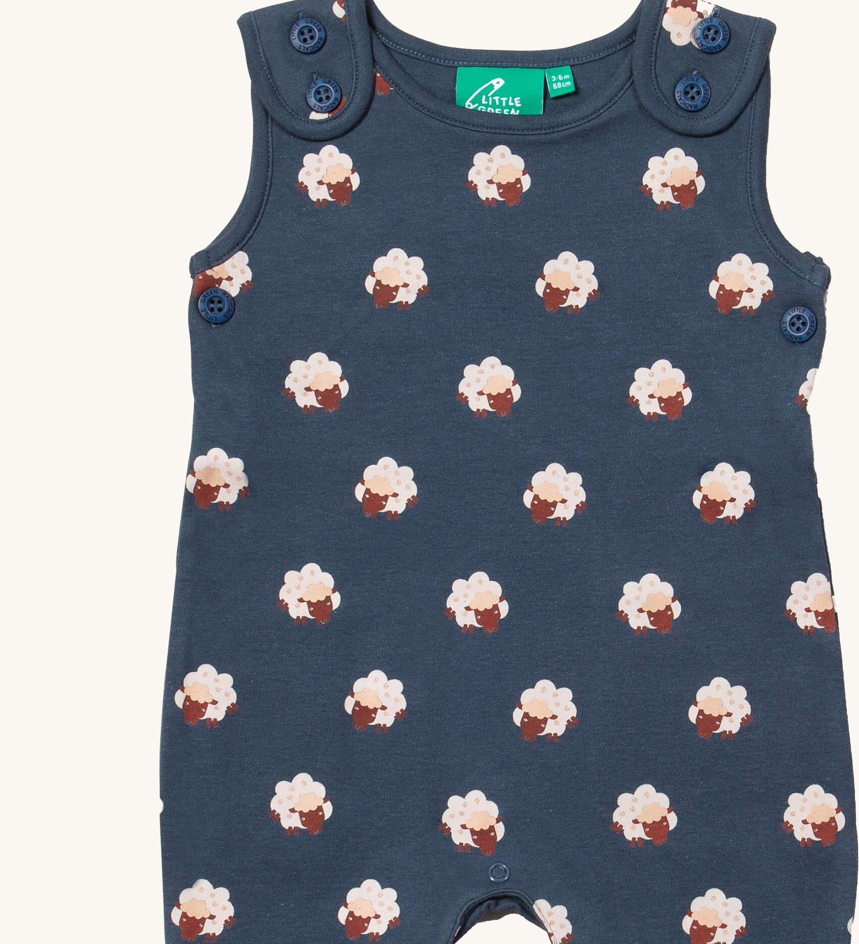 A close up of the Little Green Radicals everyday dungarees in sheep showing the button fastener detail on the shoulder straps and sheep print on navy organic cotton fabric.