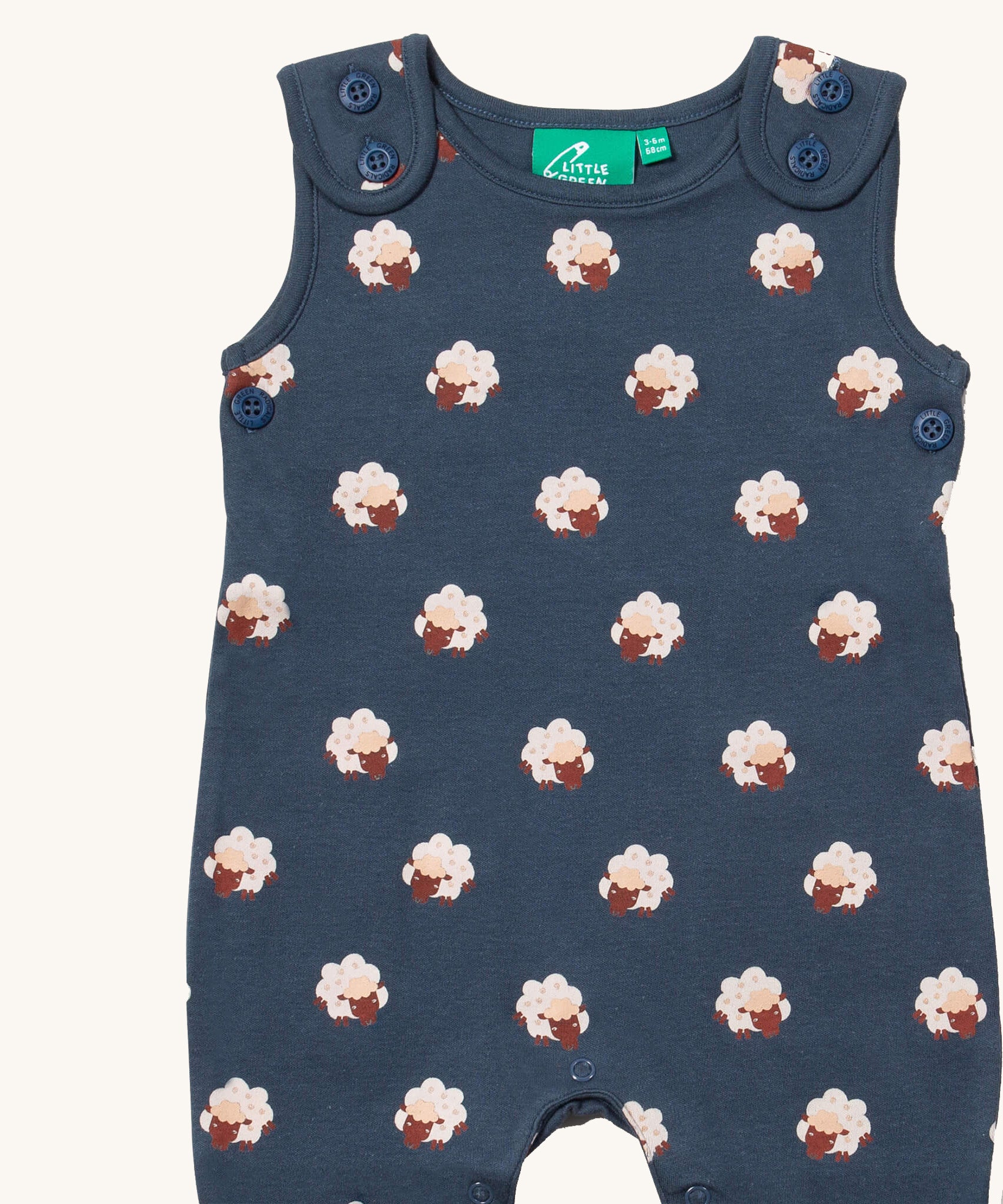 A close up of the Little Green Radicals everyday dungarees in sheep showing the button fastener detail on the shoulder straps and sheep print on navy organic cotton fabric.