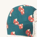 A close up of the Little Green Radials sherpa fleece cosy hat in foxes. Showing the cute fox print detail and stitching detail on turquoise organic cotton fabric