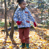 A child walking through leaves in a woodland playing with sticks and wearing the Little Green Radicals comfy corduroy trousers in ginger.  A corduroy loose fitted trousers in dark orange organic cotton fabric