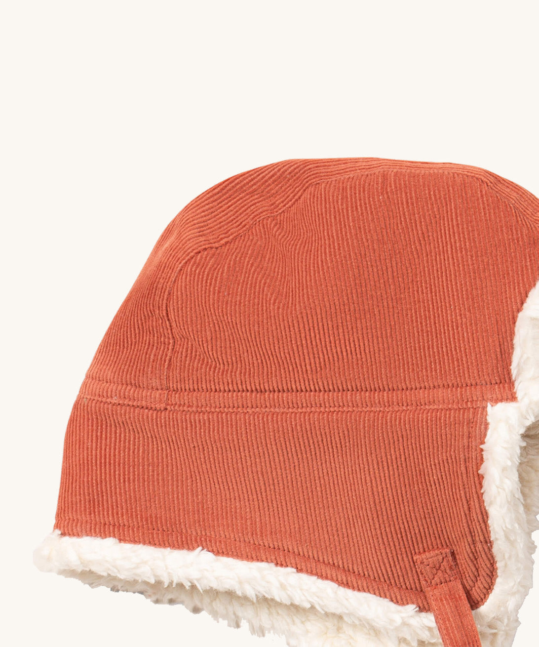 A close up of the Little Green Radicals sherpa fleece cosy hat in ginger. Showing the corduroy detail  on dark orange organic cotton fabric