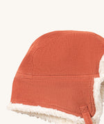A close up of the Little Green Radicals sherpa fleece cosy hat in ginger. Showing the corduroy detail  on dark orange organic cotton fabric