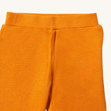 A close up of the Little Green Radicals golden waffle leggings showing the elasticated waistband detail and the waffle texture on yellow organic cotton fabric.