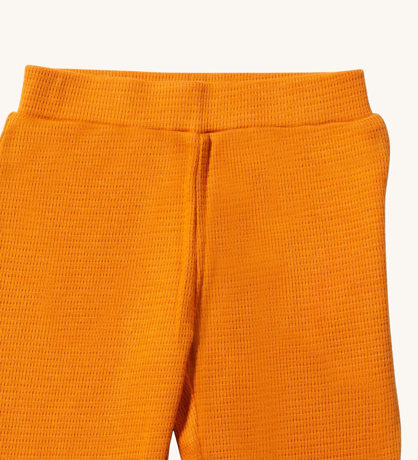 A close up of the Little Green Radicals golden waffle leggings showing the elasticated waistband detail and the waffle texture on yellow organic cotton fabric.