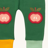 A close up of the Little Green Radicals kneepatch joggers in red apples showing the yellow and light green cuff detail organic cotton fabric 
