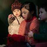 A child wearing the Little Green Radicals knitted cardigan in puddle ducks outside under a shelter 