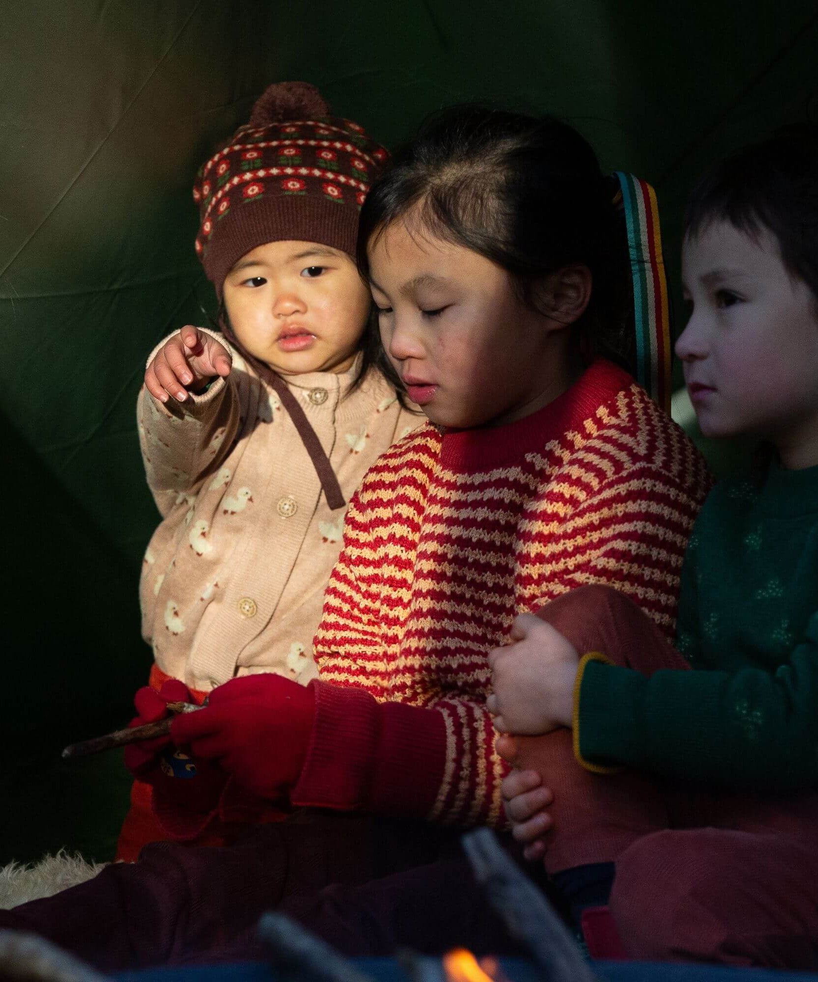 A child wearing the Little Green Radicals knitted cardigan in puddle ducks outside under a shelter 