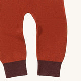 A close up of the Little Green Radicals ginger knitted leggings showing the knitted detail and contrast dark red leg cuff on dark orange organic cotton fabric