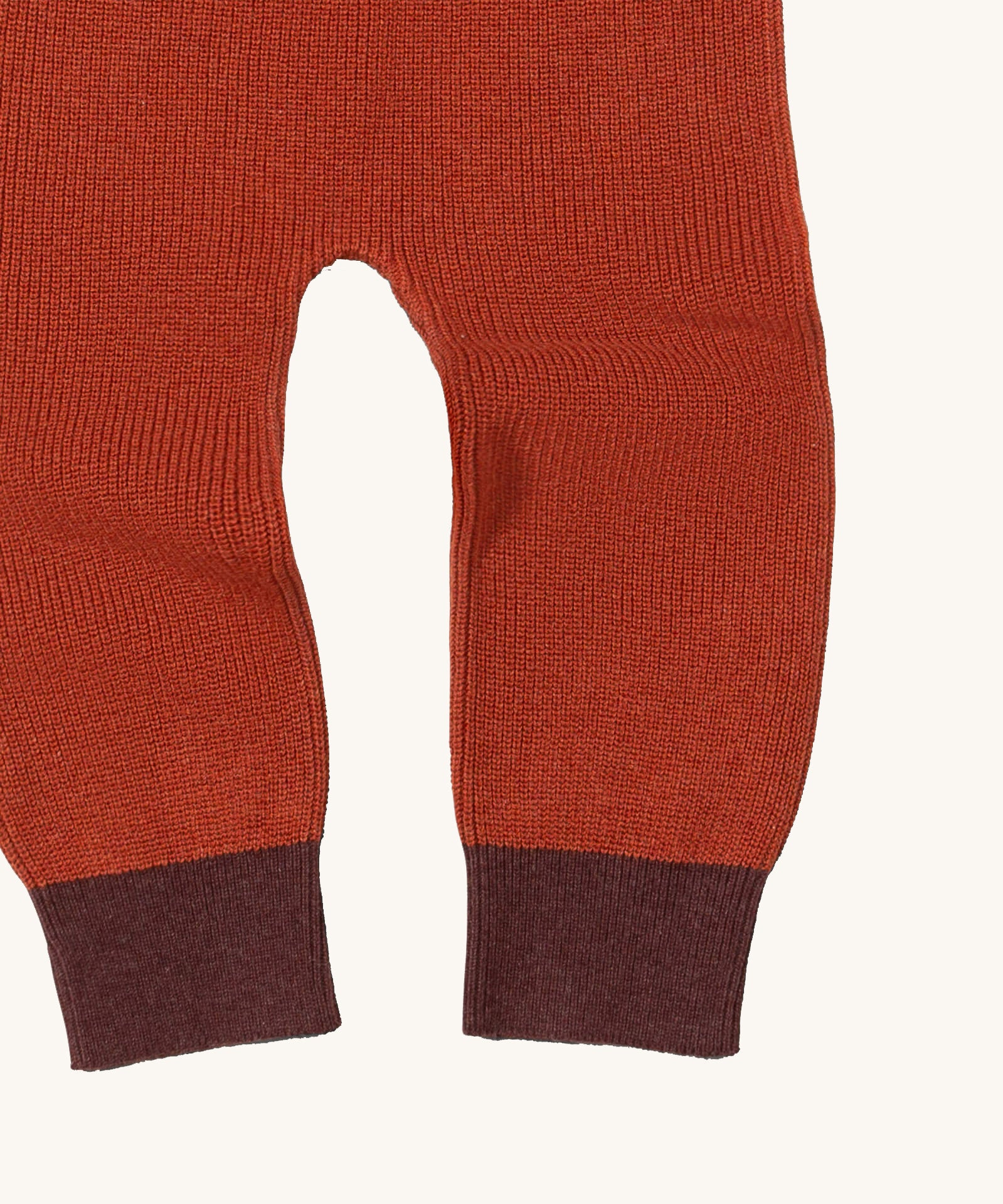 A close up of the Little Green Radicals ginger knitted leggings showing the knitted detail and contrast dark red leg cuff on dark orange organic cotton fabric