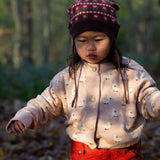 A child wearing the soft pink Little Green Radicals knitted cardigan in puddle ducks outside. Showing the button fasteners and a close up of the white ducks