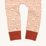 A close up of the Little Green Radicals puddle ducks knitted leggings showing the cute duck detail and red leg cuff on light pink organic cotton fabric