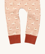 A close up of the Little Green Radicals puddle ducks knitted leggings showing the cute duck detail and red leg cuff on light pink organic cotton fabric