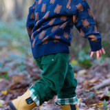 A child running in woodland and wearing the Little Green Radicals navy teddy bears knitted jumper that's available at Babipur. A soft knit jumper with cute brown bears on navy organic cotton fabric.