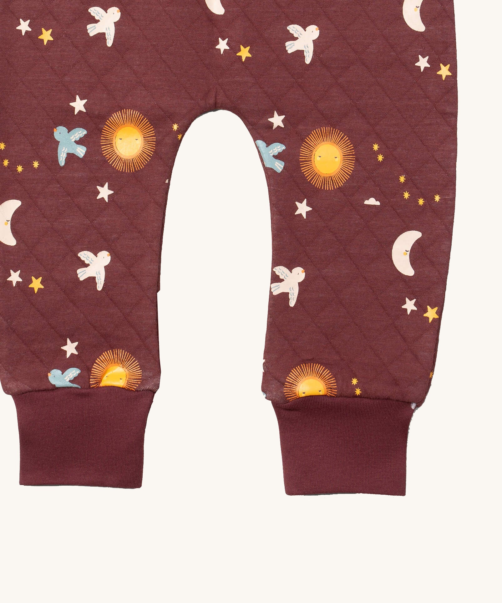 A close up of the Little Green Radicals flying birds quilted joggers. Showing the quilted stitch and elasticated leg cuff detail on dark maroon organic cotton fabric.