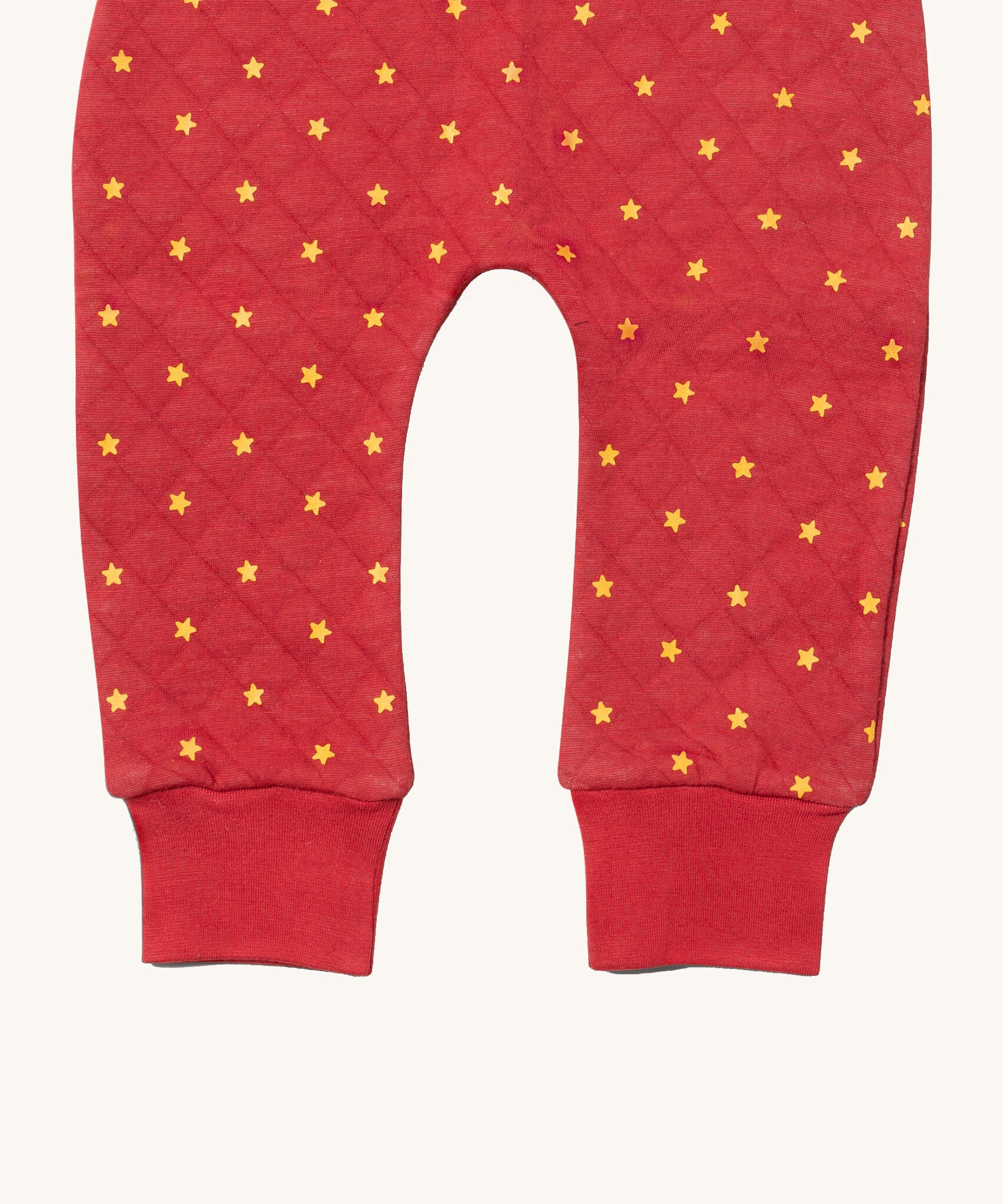 A close up of the Little Green Radicals red star quilted joggers. Showing the quilted stitch and elasticated leg cuff detail on red organic cotton fabric.