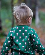 A child standing in woodland and wearing  the Little Green Radicals brown owl raglan sweatshirt that's available at Babipur. A soft knit long sleeve sweatshirt with cute brown on green organic cotton fabric.