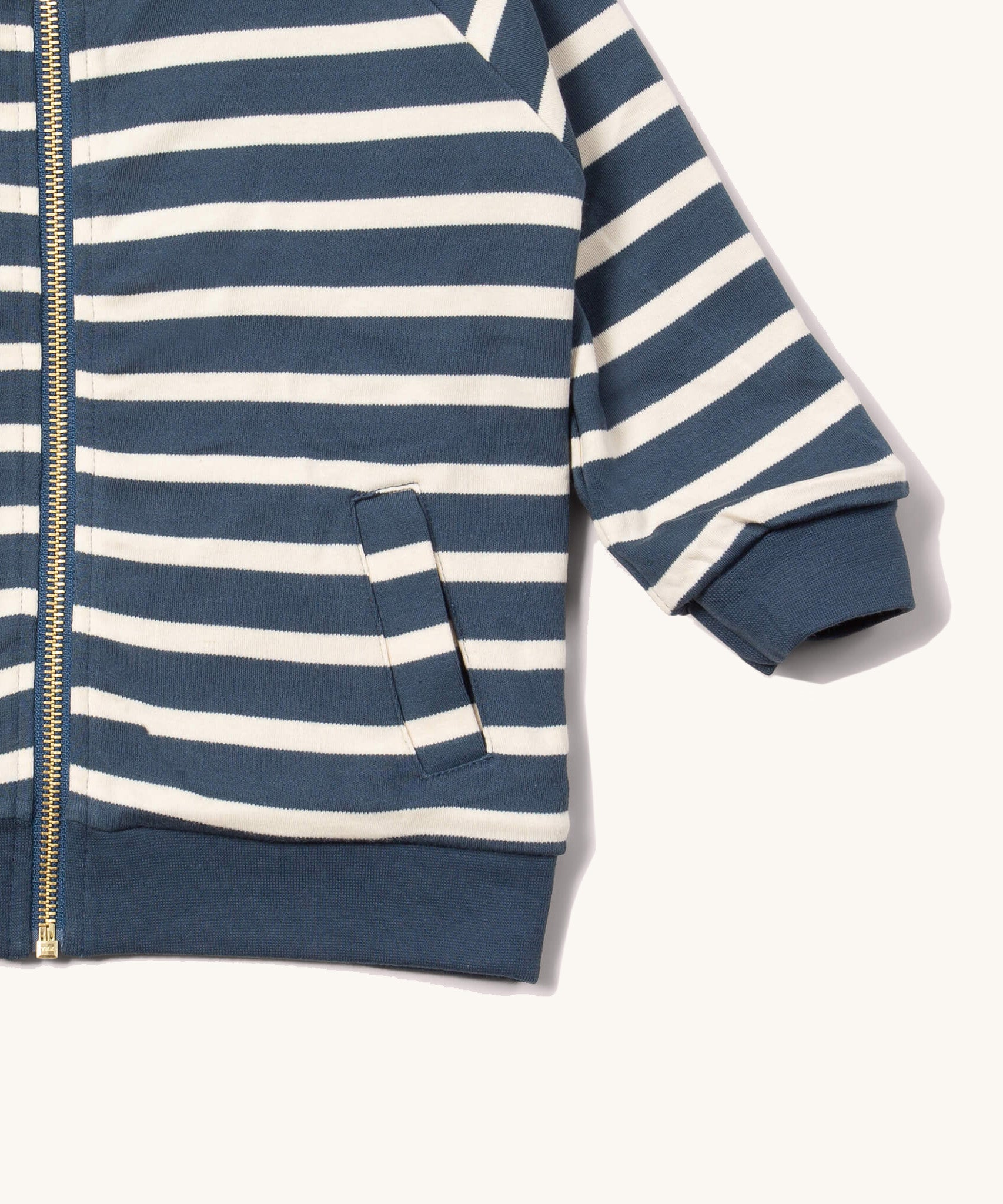A close up of the Little Green Radicals reversible easy rider jacket in sleeping sheep. Showing the pouch pocket detail and a close up of the navy and white stripe design on GOTS organic cotton fabric