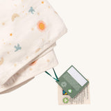 A close up of the  folded Little Green Radicals sun and moon sherpa hooded blanket. Showing the white trim detail around the edge of the blanket