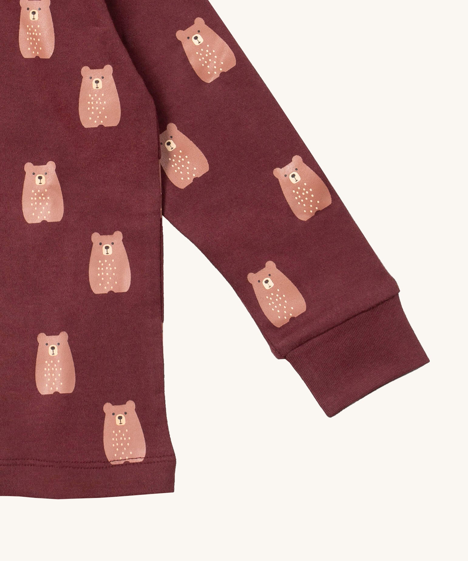 A close up of the Little Green Radicals brown bear pyjama set showing the elasticated cuff detail and a close up of the cute brown bear on organic cotton fabric.