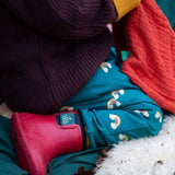 A close up of a child sitting down and wearing the Little Green Radicals turquoise rainbow joggers showing the print detail on organic cotton fabric.