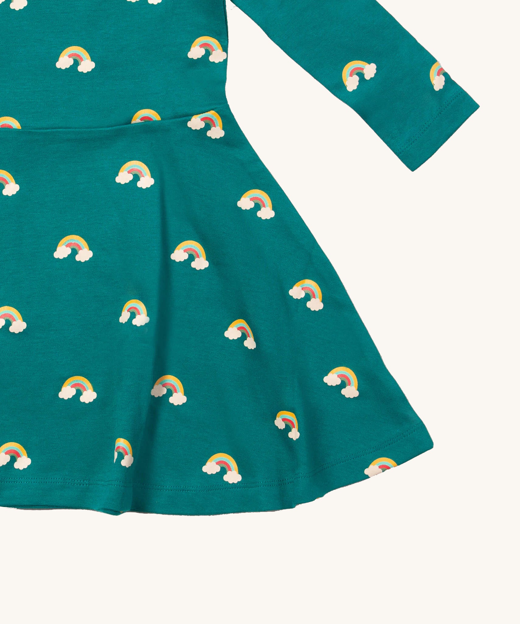A close up of the Little Green Radicals rainbow turquoise twirly dress showing the gentle gather detail on organic cotton fabric.