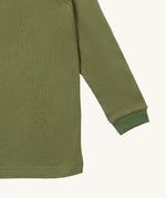A close up of the Little Green Radicals green chive waffle long sleeve cosy top cuff and hem detail on green organic fabric