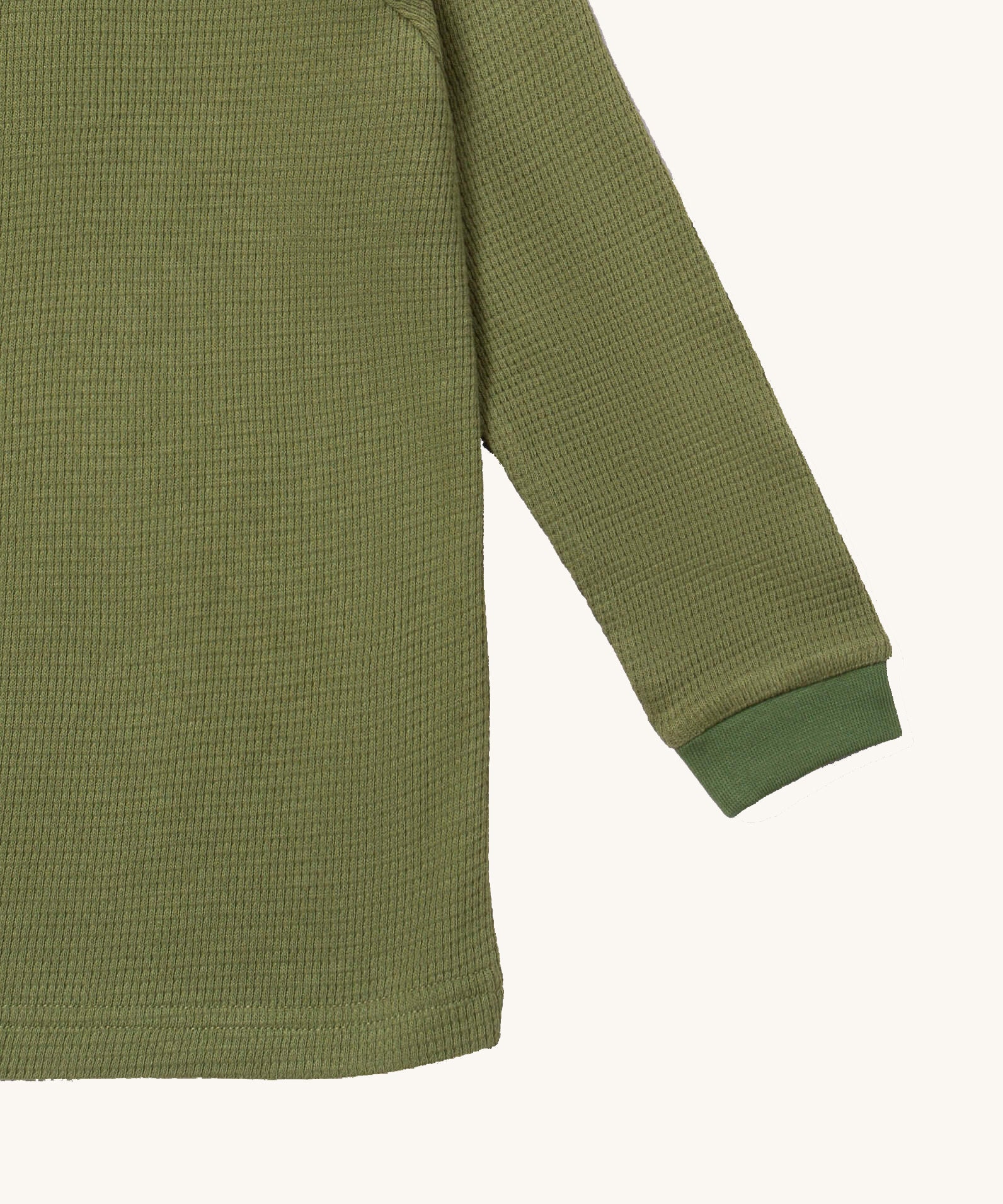 A close up of the Little Green Radicals green chive waffle long sleeve cosy top cuff and hem detail on green organic fabric
