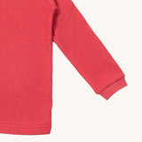 A close up of the Little Green Radicals pink berry waffle long sleeve cosy top cuff and hem detail on pink organic fabric