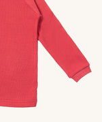 A close up of the Little Green Radicals pink berry waffle long sleeve cosy top cuff and hem detail on pink organic fabric