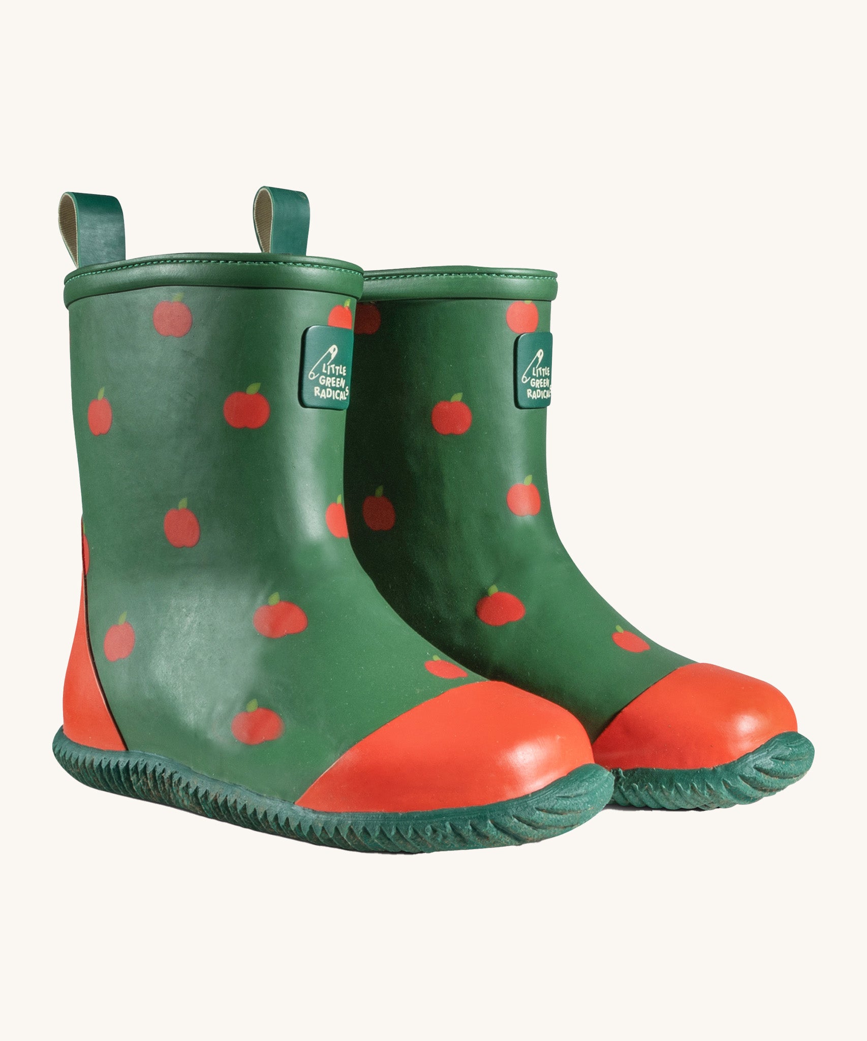 A pair of Little Green Radicals kid wellington boots. Natural rubber waterproof wellies in green with red apples printed all over. Features a red toe cap, gripped sole and pull-on tab for easy fitting