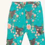 A close up of the Little Green Radicals winter rabbit pyjama bottom showing the elasticated waist band detail with a close up of the rabbit in pink flowers print detail on turquoise organic cotton fabric.