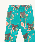 A close up of the Little Green Radicals winter rabbit pyjama bottom showing the elasticated waist band detail with a close up of the rabbit in pink flowers print detail on turquoise organic cotton fabric.