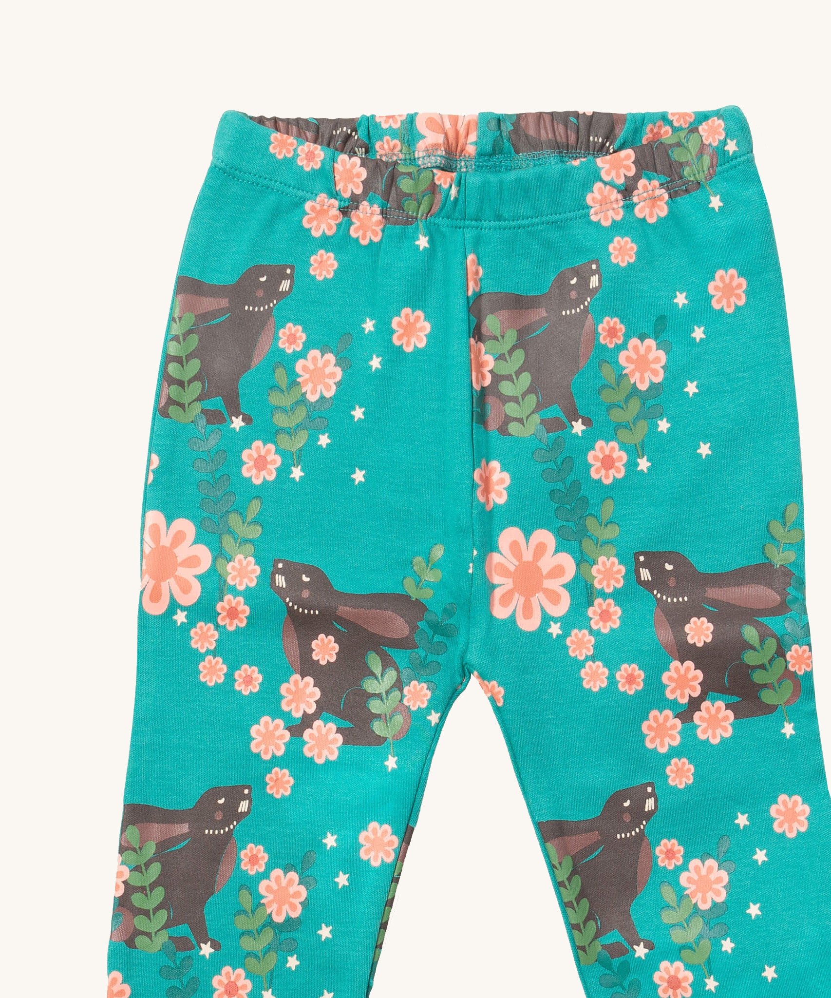 A close up of the Little Green Radicals winter rabbit pyjama bottom showing the elasticated waist band detail with a close up of the rabbit in pink flowers print detail on turquoise organic cotton fabric.