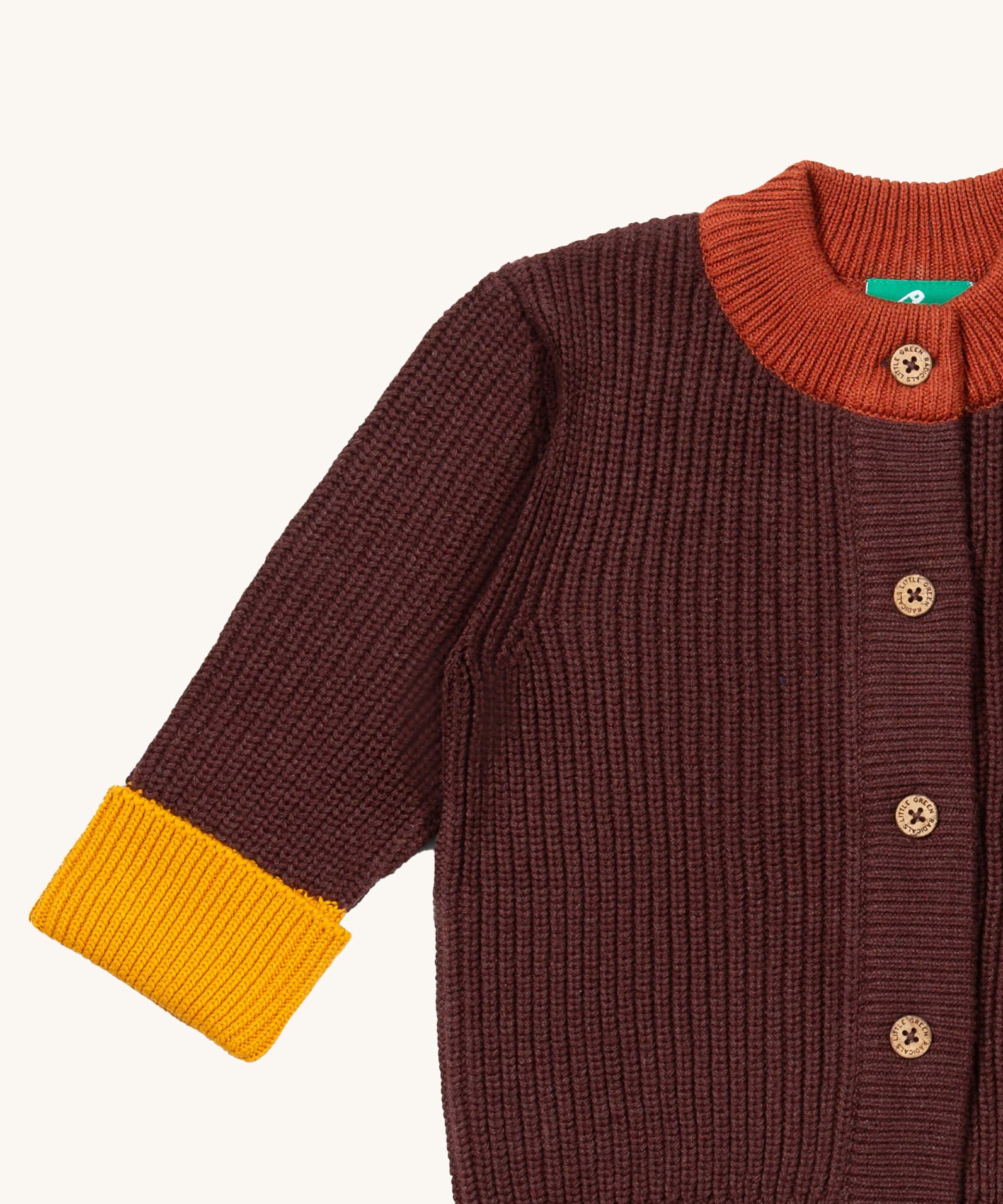 A close up of the Little Green Radicals knitted cardigan in chocolate showing the button detail and a close up collar and cuff detail on brown  GOTS organic cotton fabric and available at Babipur.