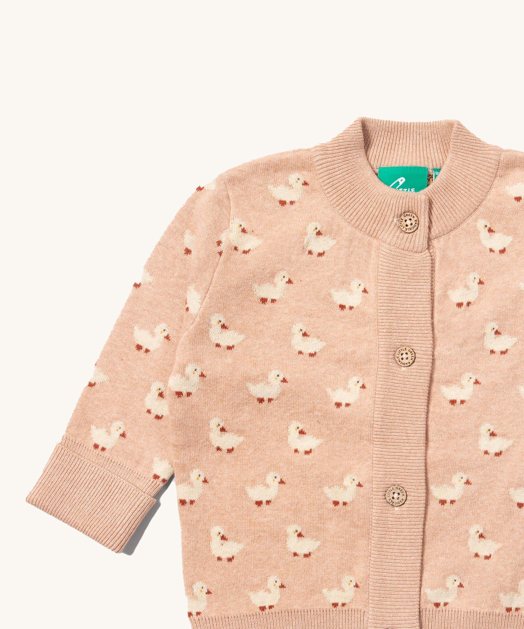 A close up of the Little Green Radicals knitted cardigan in puddle ducks showing the button detail and a close up of the white ducks on the soft pink GOTS organic cotton fabric and available at Babipur.