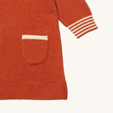 A close up of the Little Green Radicals ginger knitted collar dress. showing the pouch pocket and striped cuff detail on dark orange organic cotton fabric