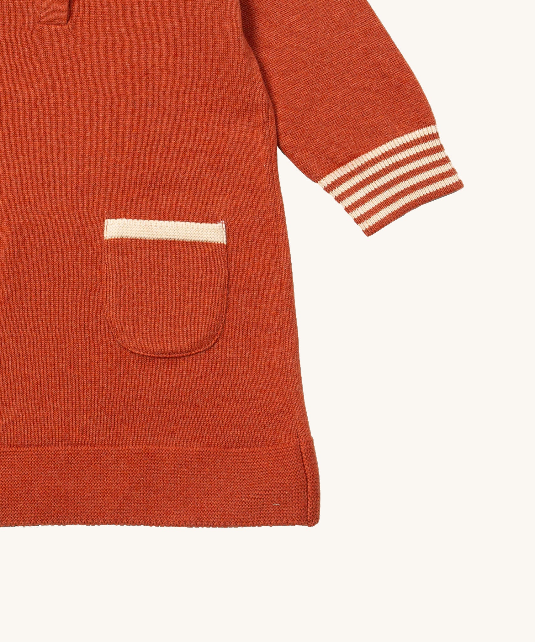 A close up of the Little Green Radicals ginger knitted collar dress. showing the pouch pocket and striped cuff detail on dark orange organic cotton fabric