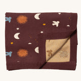 Little Green Radicals baby blanket in flying birds. A GOTS organic cotton blanket in brown with cute birds flying around the stars, the moon and the sun. Features a matching textured brown border and a yellow striped textured inner.